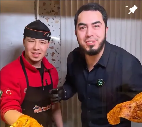 Ayla tantuni oshpazi va mehmon nonga o'ralgan tantunini kameraga ko'rsatmoqda